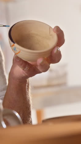 female potter painting a bowl