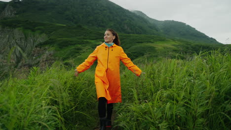 woman hiking in mountains wearing an orange raincoat