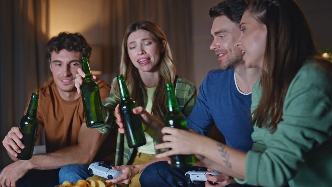 Smiling buddies clinking bottles at weekend home hangout close up. Happy friends