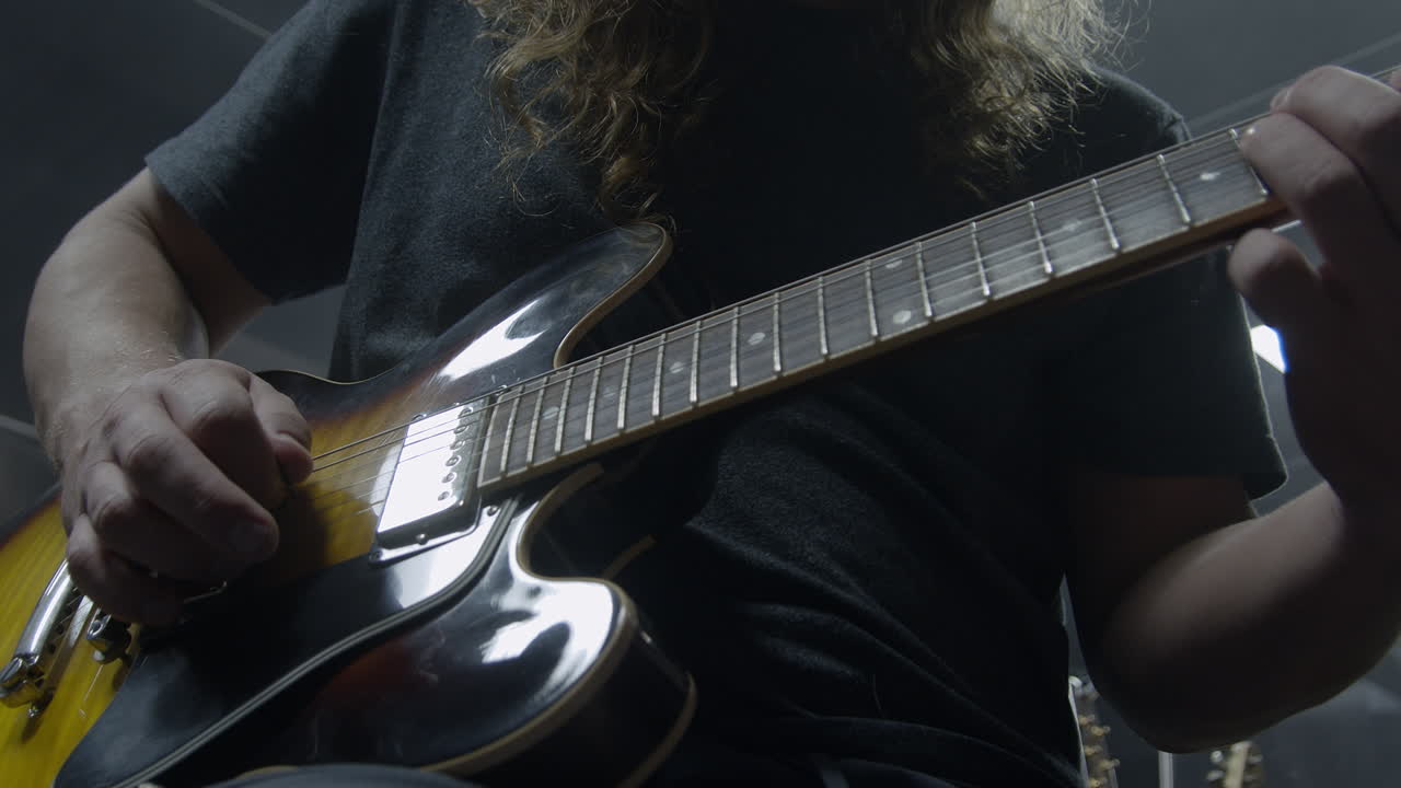 Rocker dai capelli lunghi che suona la chitarra in studio