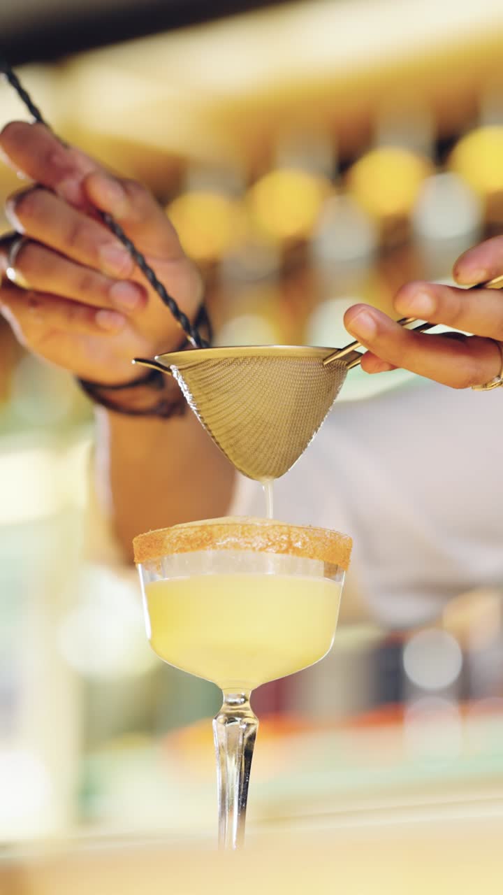Barman che filtra un cocktail rinfrescante in un bicchiere