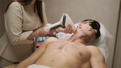 esteticista profesional aplica tratamiento con láser al cuello de un paciente masculino para la depilación en un spa médico