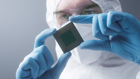 close-up of repairman in protective uniform holding computer processor, removing chip cpu. technologies and developments concept. technician engineer looking at detail for gadget