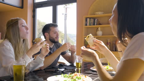 close up view of group of friends talking and eating pizza at restaurant table