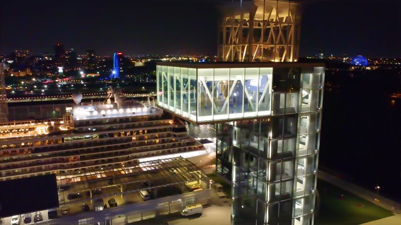 Night View of Modern Glass Tower and Cruise Ship at Dock