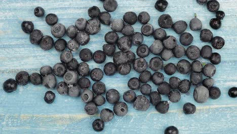 Timelapse-footage-of-freezing-fruits,-berries-on-blue-surface.-Frozen-food.-Frosting-of-blueberry