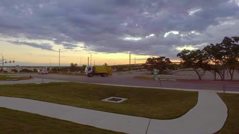 Trash-truck-pulling-out-of-empty-car-park-at-sunrise