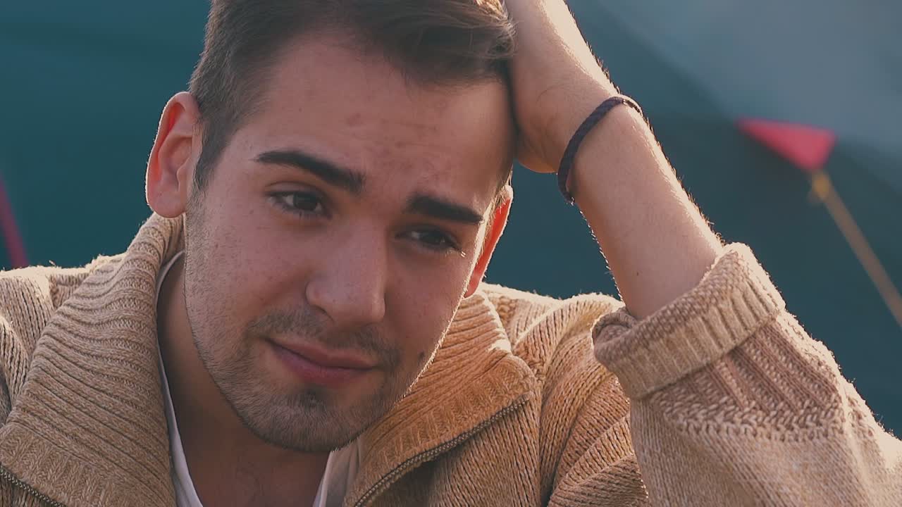 un tipo frustrado se sienta con la mano en la cabeza contra la tienda azul