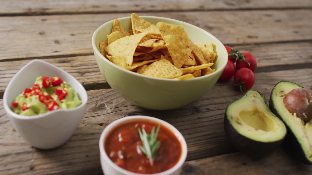 video de chips de tortilla, guacamole y salsa en una superficie de madera