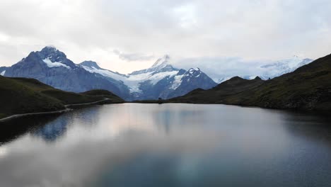 Aerial-flyover-over-lake-Bachalpsee-in-Grindelwald-First,-Switzerland-with-a-view-of-Schreckhorn-and-other-Bernese-Oberland-peaks-in-the-reflection