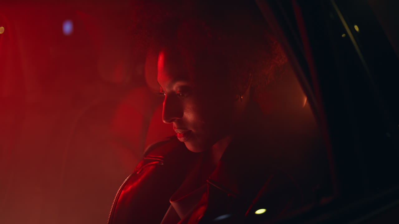 Woman illuminated neon light sitting car backseat alone closeup. lady