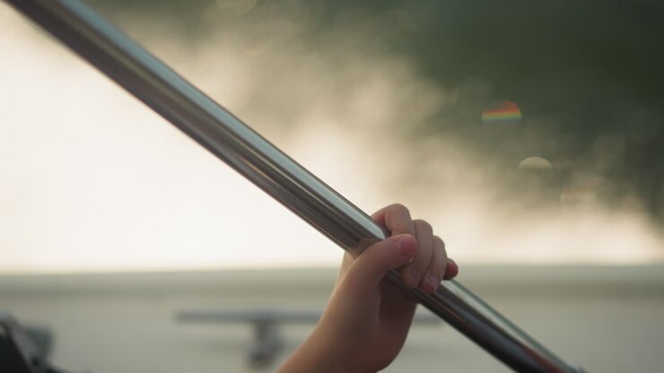 Child holds steel pipe by hand while rides motor boat under rainy cloud in summer closeup. Kid enjoys yacht sailing at seaside time lapse. Family vacation activity