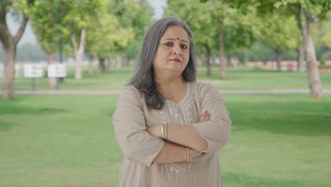 Confident-Indian-old-woman-standing-crossed-hands-in-park