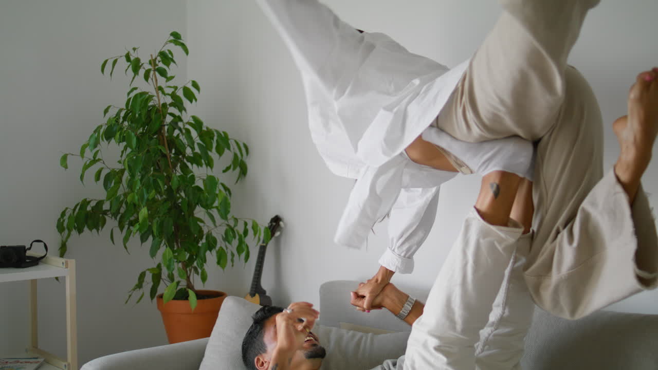 романтические молодожены играют на диване дома вблизи. положительная семья веселится на диване