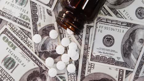 lots of dollar bank notes scattered with pills on table