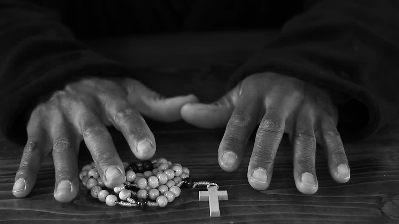 Bidden tot God met gevouwen handen, met kruis en met mensen, zwarte achtergrond, stockvideo, stockbeelden.