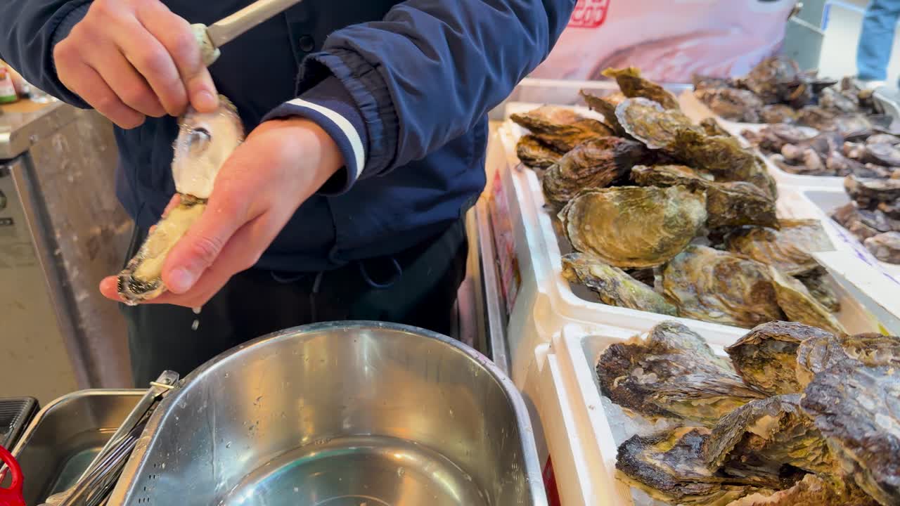 Close-up shot of a vendor skillfully shucking raw oysters at a Tokyo seafood market