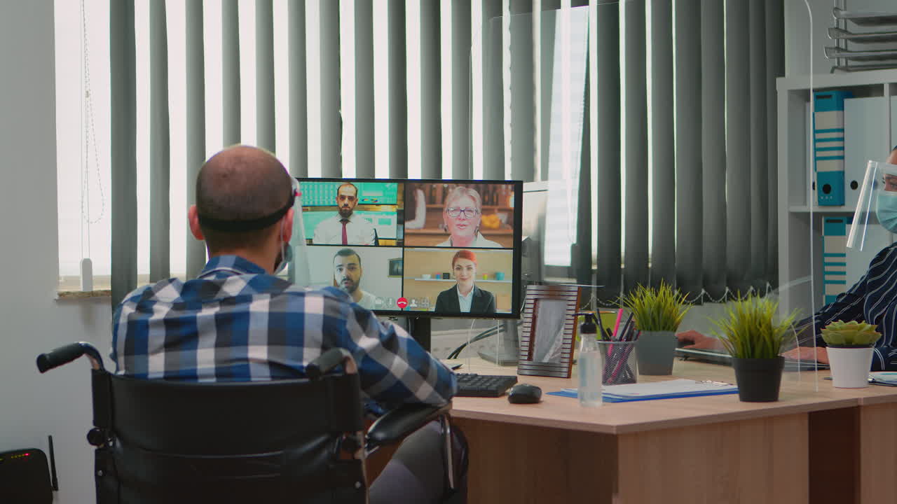Manager in wheelchair talking with mask during videocall