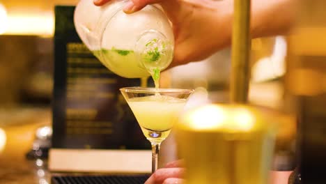 bartender pouring cocktail into a glass