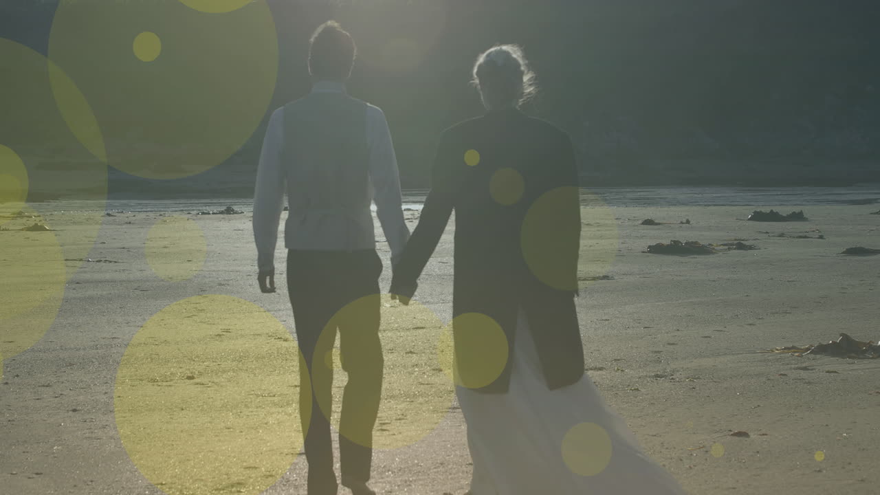 Animation of light spots over caucasian couple walking and holding hands
