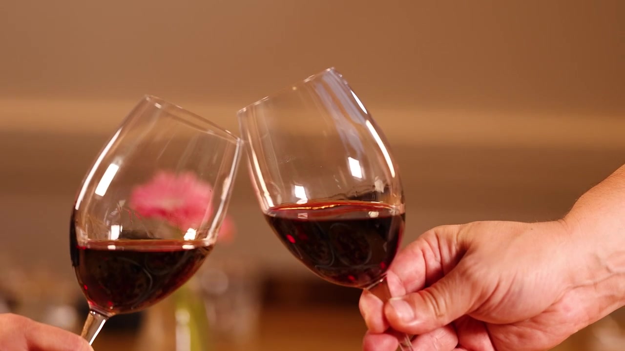 Dos personas brindando con copas de vino tinto
