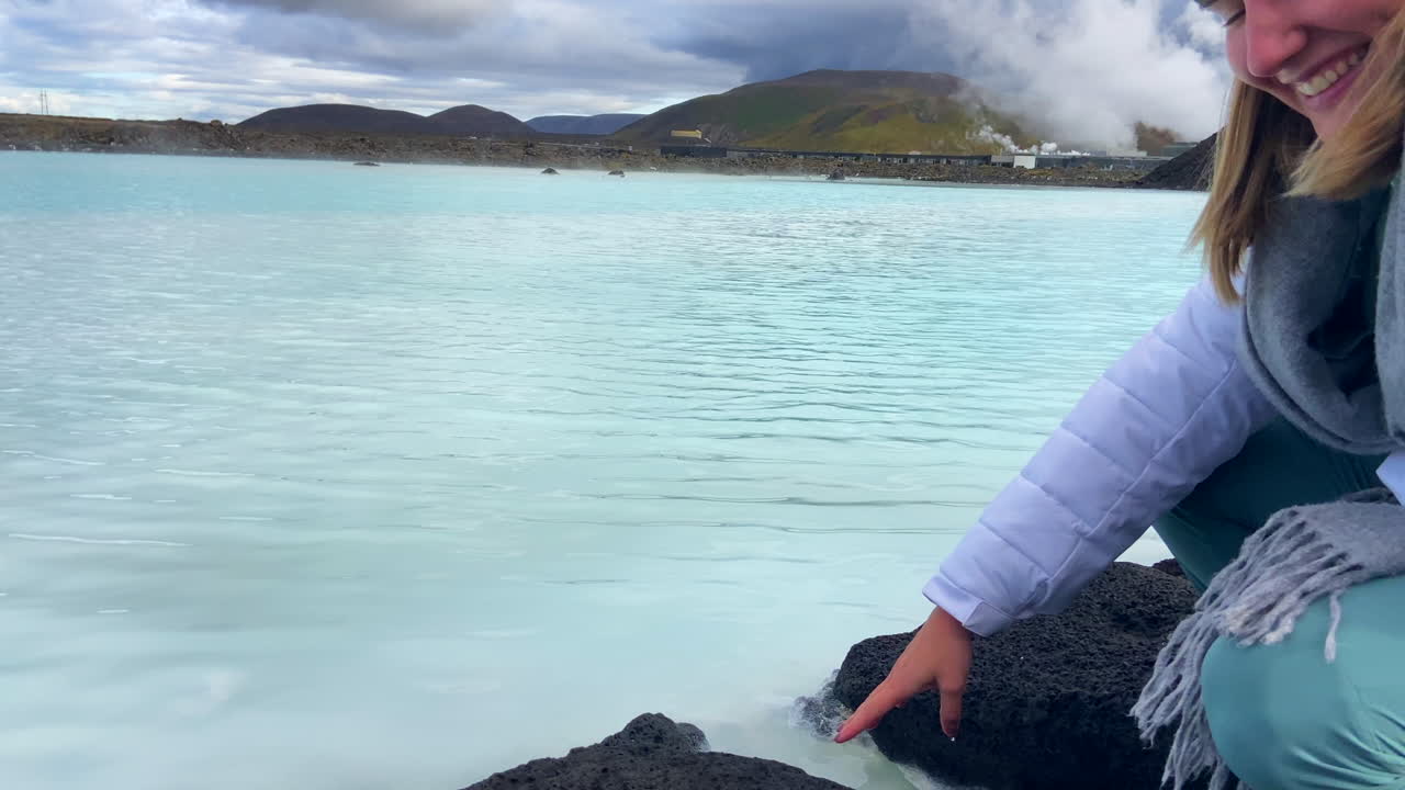 una joven rubia feliz probando el agua geotérmica de la laguna azul en islandia