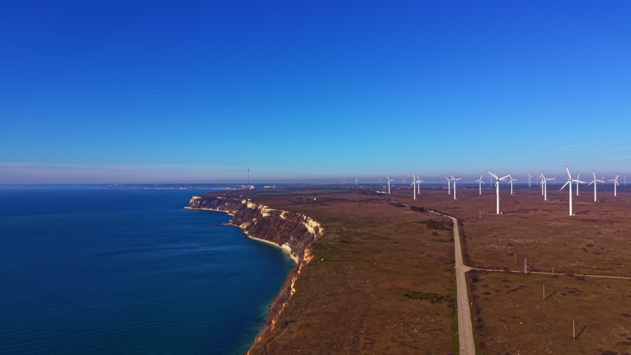 Paesaggio costiero con turbine eoliche e cielo azzurro terso vicino alla costa a mezzogiorno