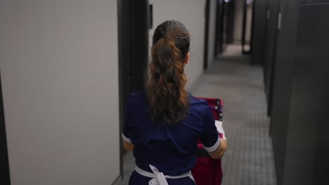 hotel maid pushing a cart in a hallway