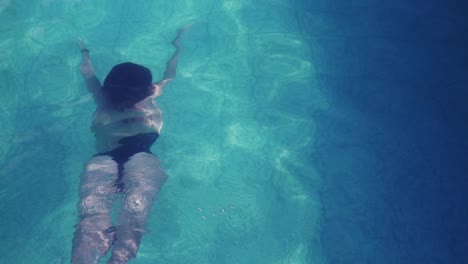 una mujer delgada nadando bajo el agua lejos de la cámara