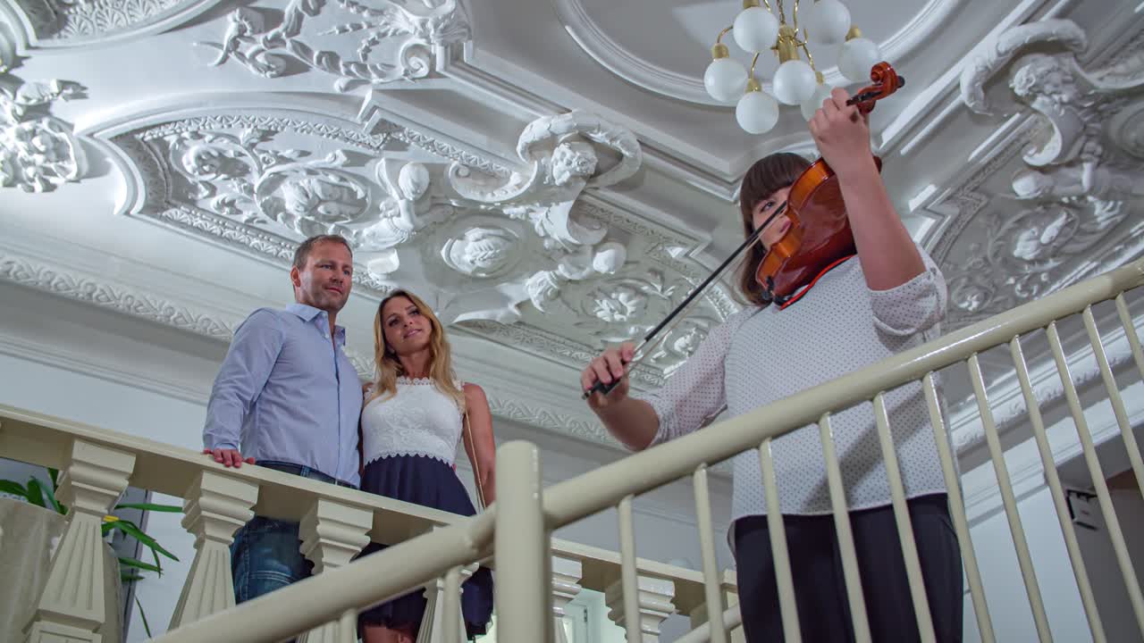 Lovely couple admiring a violinist playing at a property