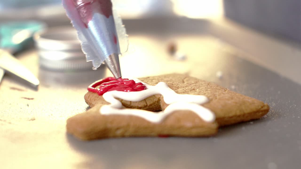 Close up isolated shot of piping pastry bag, decorating gingerbread cookie with coloured sugar icing 4k