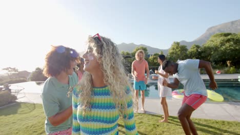 Happy-caucasian-woman-dancing-at-sunny-pool-party-with-diverse-friends,-slow-motion