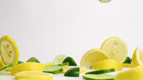 Bright-fruit-medley-of-lemon-and-lime-wedges-and-slices-falling-and-bouncing-on-white-backdrop-in-slow-motion