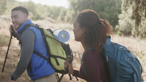 happy african american couple hiking with trekking poles in forest, slow motion