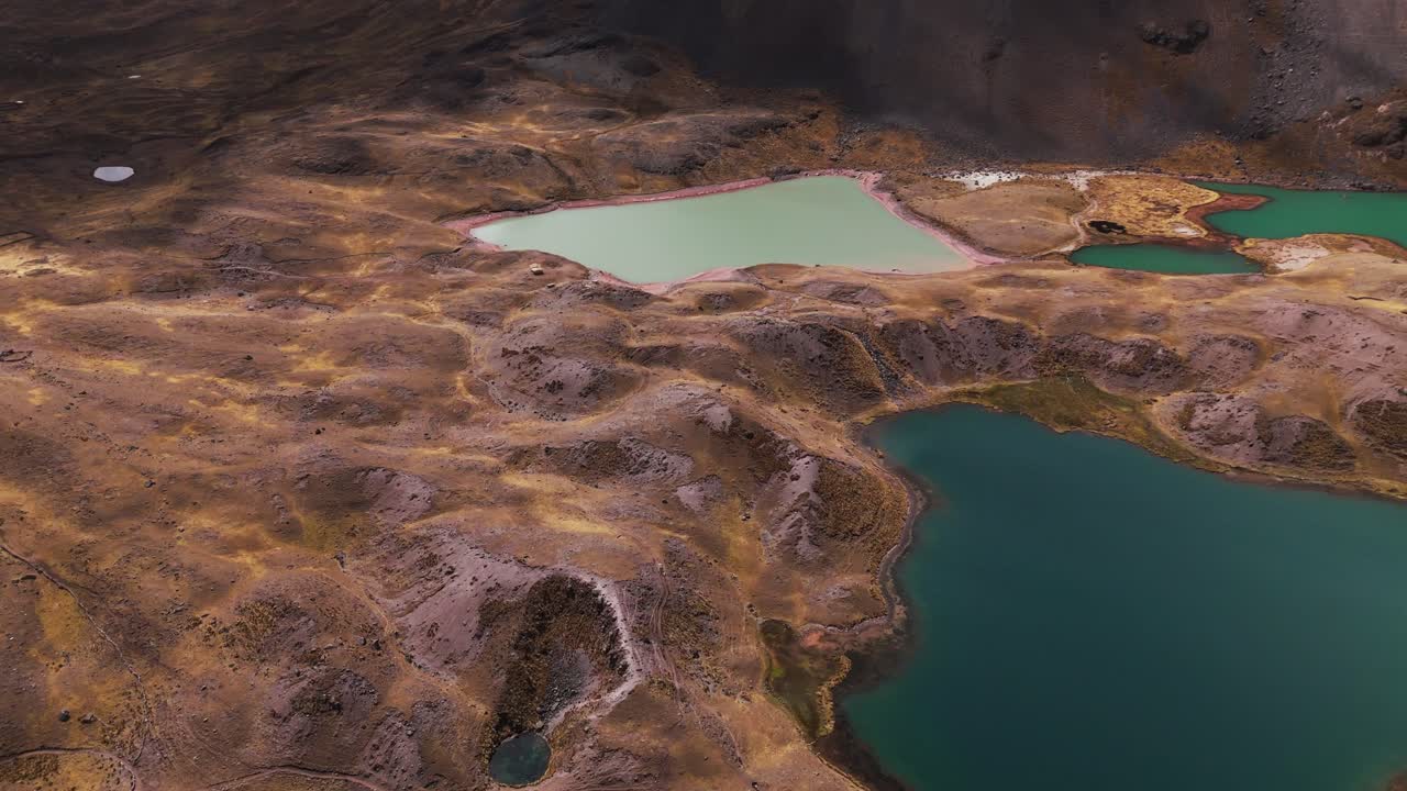 Aerial overview of one of the 7 Lagoons of Ausangate, Cusco, Peru, surrounded by mountain peaks, high angle dolly