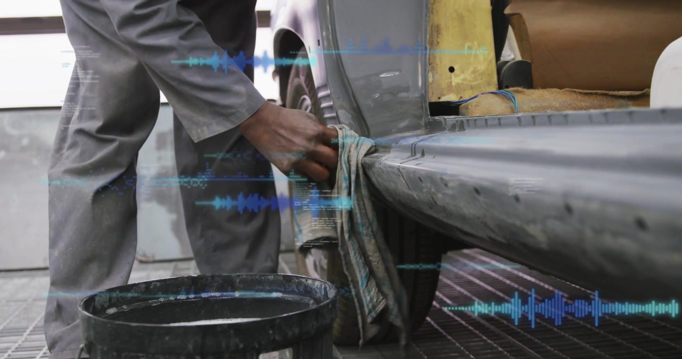 Male auto repair worker holding rag near bumper, prepping panel as blue overlays tracking wipe