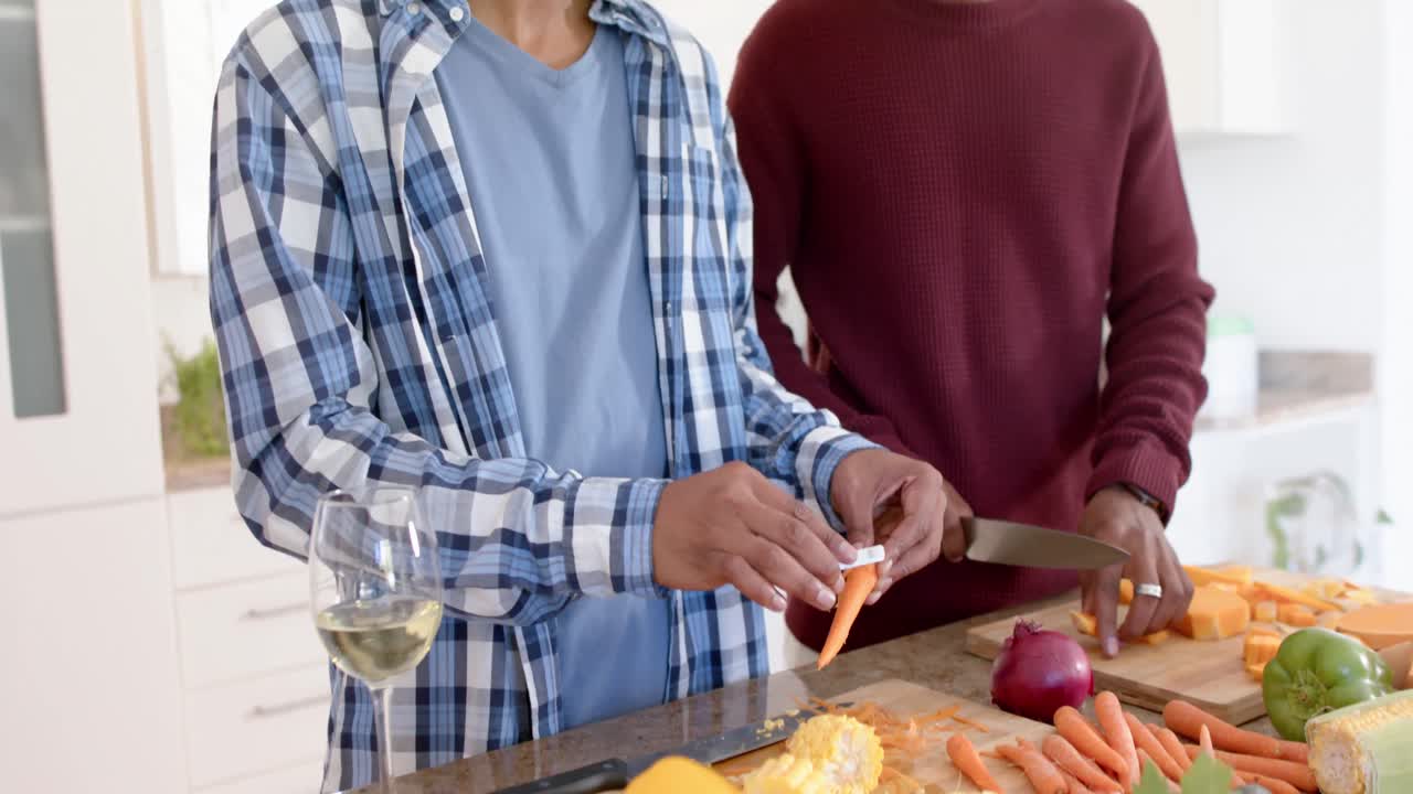 pareja feliz afroamericana de hombres homosexuales preparando la cena, cortando verduras en la cocina, cámara lenta