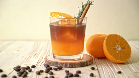 A-glass-of-iced-americano-black-coffee-and-layer-of-orange-and-lemon-juice-decorated-with-rosemary-and-cinnamon