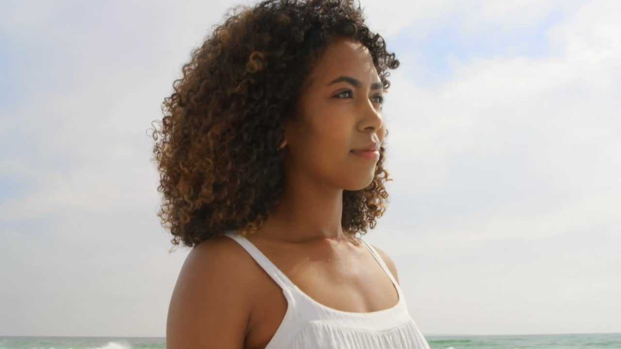 vista lateral de una mujer afroamericana caminando por la playa 4k