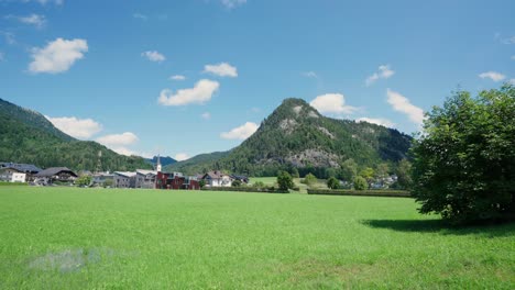 Grass-field-with-a-small-Austrian-village-and-mountains