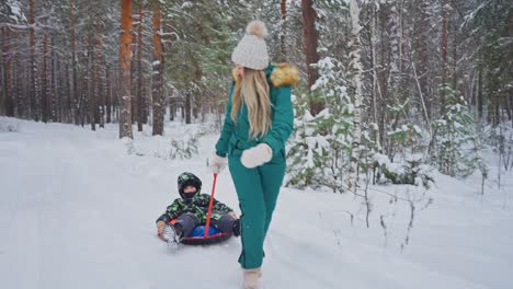 mother and child sledding in snowy forest