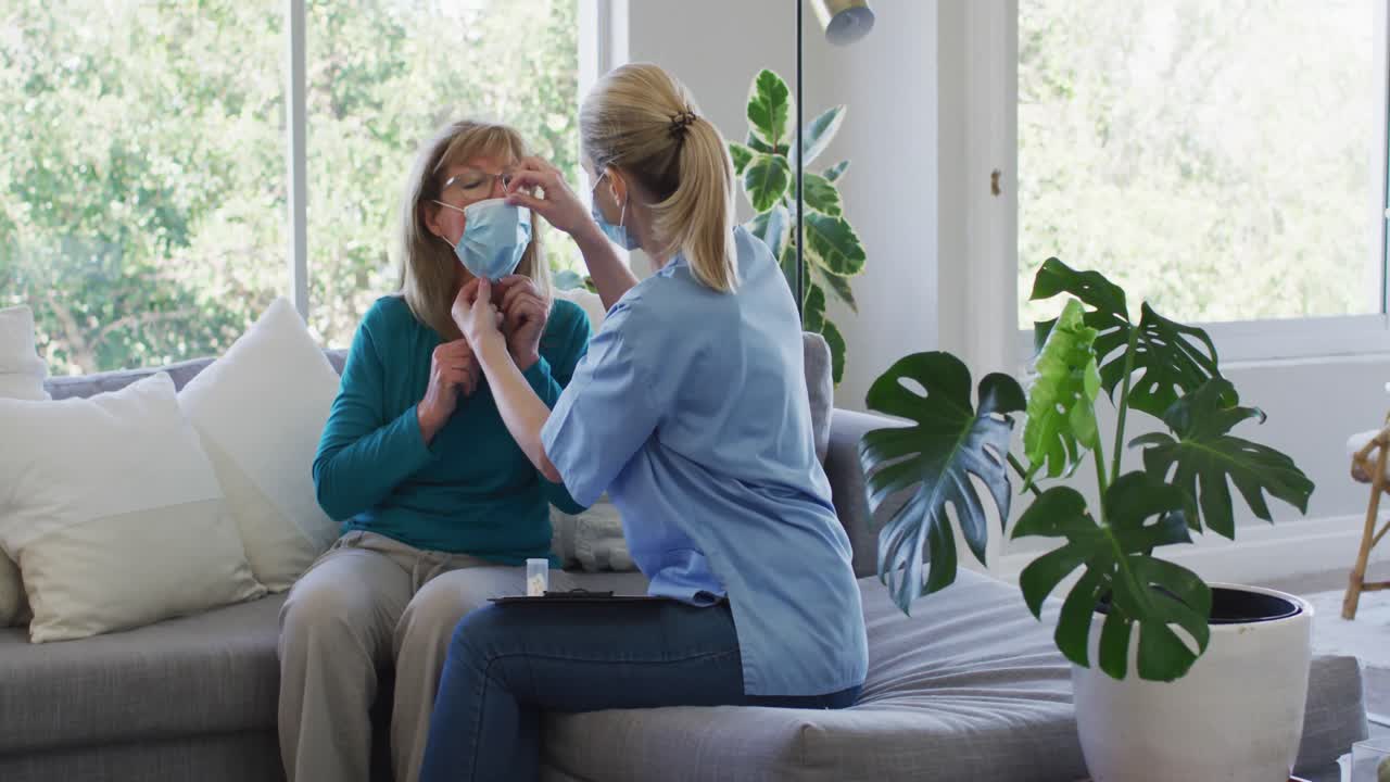 Female health worker putting face mask on senior woman at home