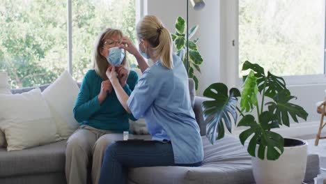 female health worker putting face mask on senior woman at home