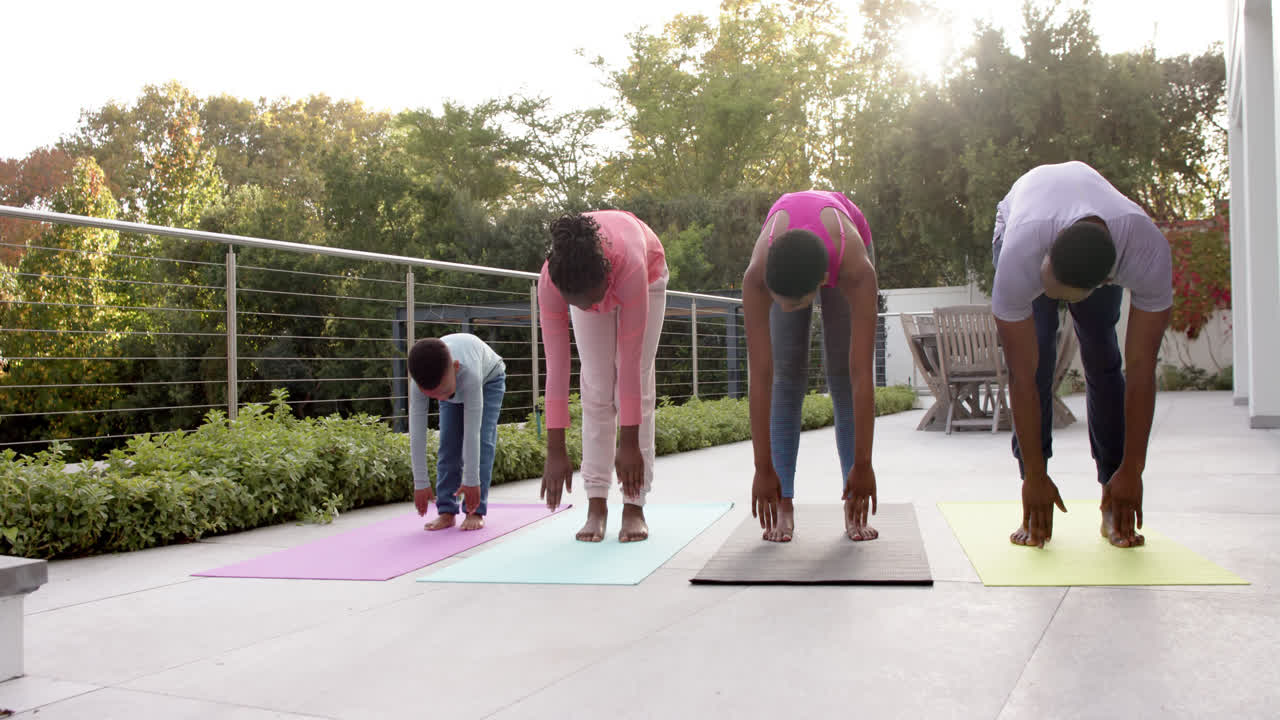 felices padres afroamericanos, hijo e hija practicando yoga en un jardín soleado, en cámara lenta.