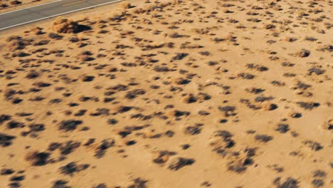 Aerial-drone-moving-forward-while-panning-up-to-reveal-a-colorful-van-driving-on-a-small-isolated-road-with-vast-large-mountains-and-landscape