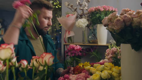 male professional florist seller collects bouquet for customer in flower shop