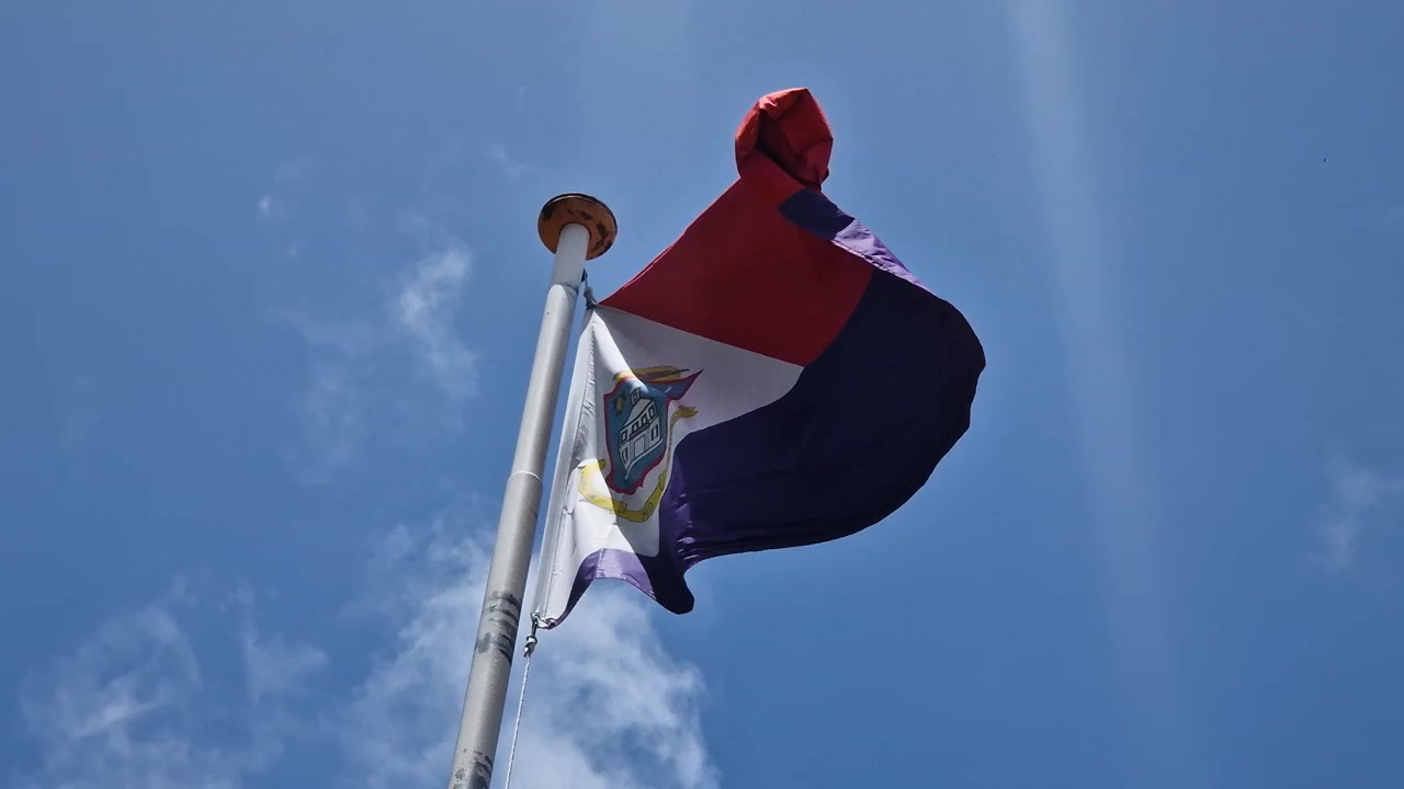 Bandiera nazionale dell'isola di Sint Maarten che sventola sull'asta in una giornata di sole, Mar dei Caraibi