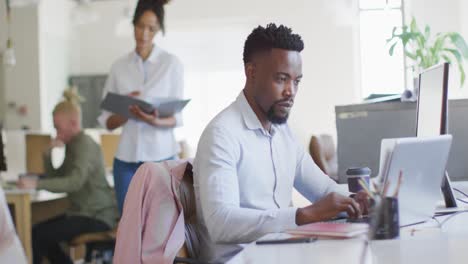 Retrato-De-Un-Feliz-Hombre-De-Negocios-Afroamericano-Usando-Una-Computadora-Portátil-En-Una-Oficina-Creativa