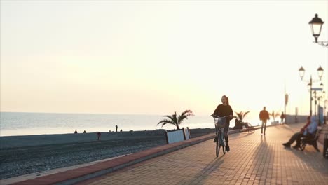 woman cycling on a coastal promenade at sunset