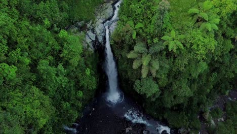Aerial-view-from-drone-flying-over-nature-view-of-waterfall-with-rocky-river-and-surrounding-vegetation
